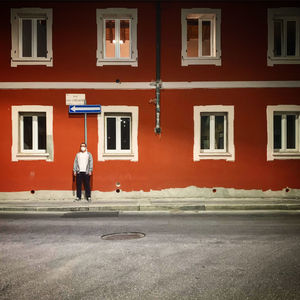 Rear view of man walking on road against building