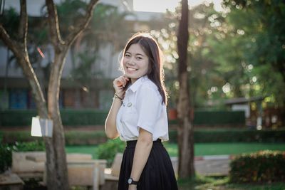 Portrait of smiling young woman standing at park