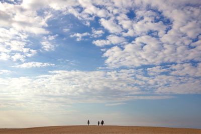 People walking on sand against sky