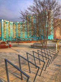 Empty benches on footpath by building against sky