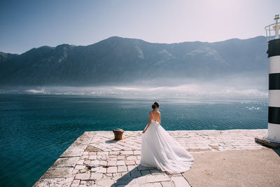 Woman with umbrella on sea against mountain