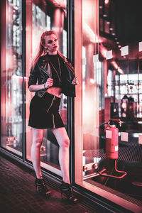 Woman standing against illuminated wall at night