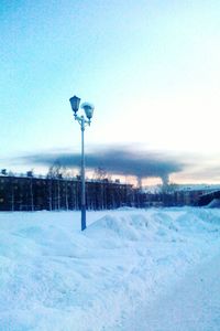 Street light on snow covered landscape against clear blue sky