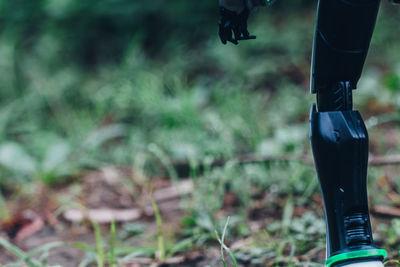 Close-up of legs of robot standing on field - futuristic sustainability / coexist tech and nature