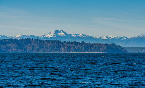 Scenic view of sea by mountains against sky