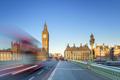 Double-decker bus passes on westminster bridge, in front of westminster palace and clock tower of big ben (elizabeth tower), london, england, united kingdom