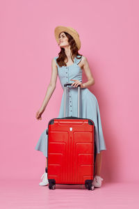 Woman wearing hat standing against pink background