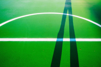 Shadow of person standing on green basketball court