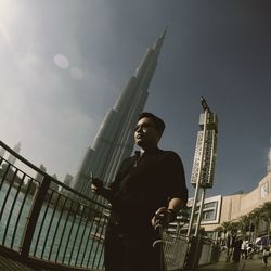 Low angle view of man standing by building against sky