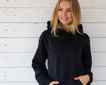 Portrait of a smiling young woman standing against wall