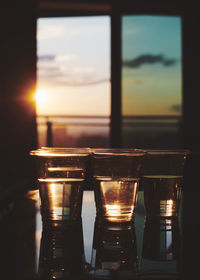 Close-up of beer glass on table against sunset sky