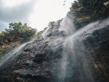 Low angle view of waterfall against sky