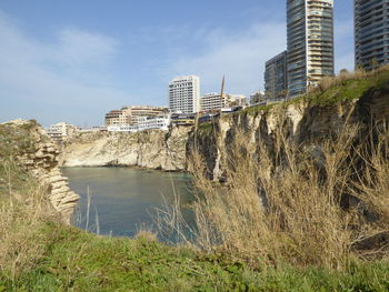 River by buildings in city against sky