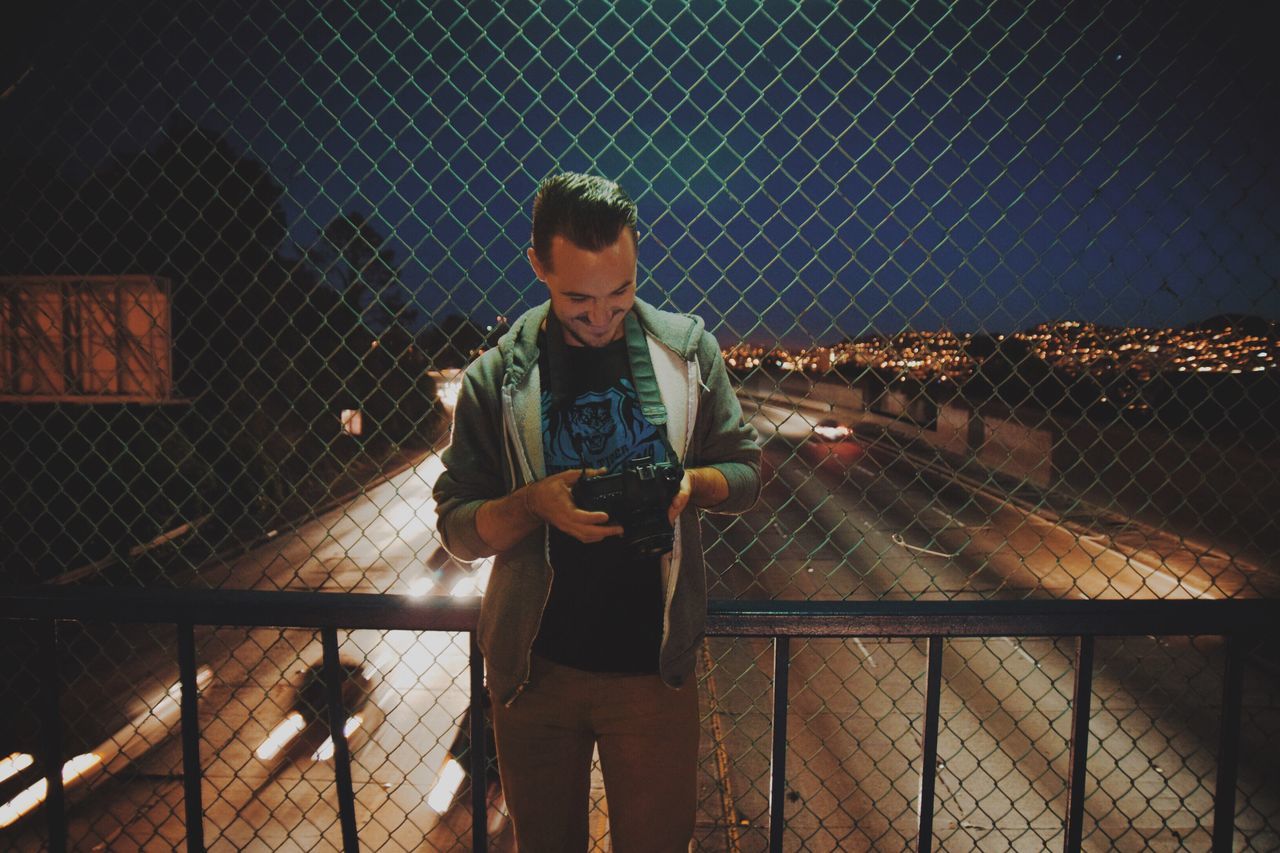 lifestyles, full length, casual clothing, railing, leisure activity, standing, built structure, architecture, person, night, looking at camera, building exterior, three quarter length, front view, portrait, illuminated, boys, young adult