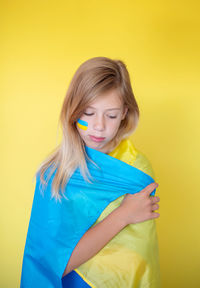 Portrait of young woman against yellow background