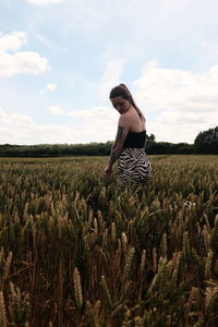 Rear view of woman standing in field against sky