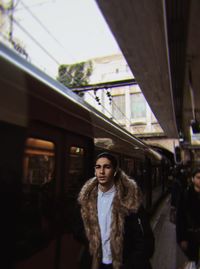 Portrait of young woman standing on railroad station