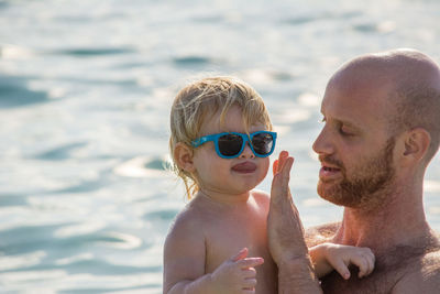 Father carrying son while standing at beach