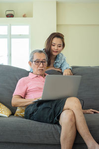 Young woman using mobile phone while sitting on sofa