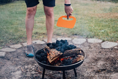 How to use a charcoal grill. man with plastic bbq hand fan near charcoal grill fire. barbeque