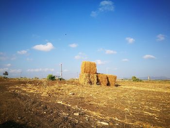 Hay bales on field against sky