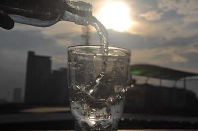 Close-up of glass bottle against sky during sunset