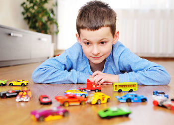 Boy with toy car lying on floor at home