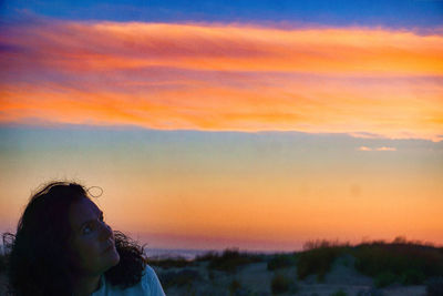 Portrait of woman standing against orange sky