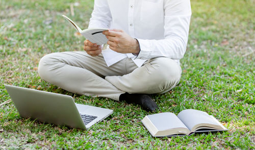 Rear view of man using mobile phone in grass