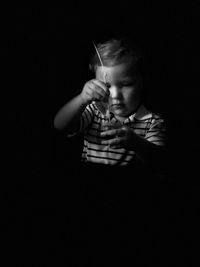 Boy holding string while standing against black background