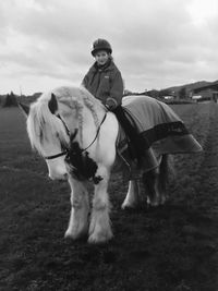 Horse riding horses on field against sky