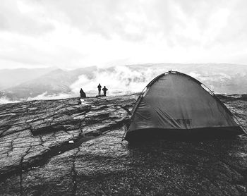 People standing on mountain by sea against sky