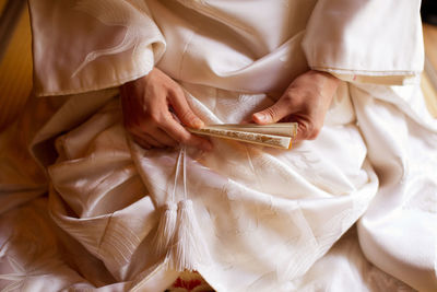 Midsection of woman holding traditional fan