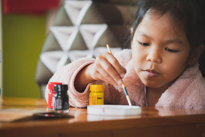 Close-up of girl painting on table at home