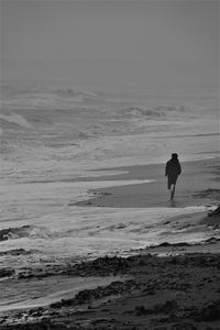 Silhouette boy on beach against sky