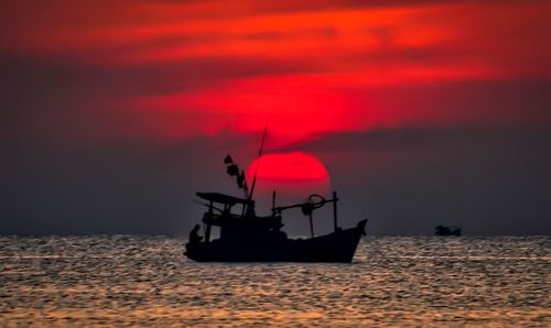 Boat sailing in sea at sunset