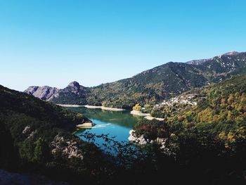 Scenic view of river and mountains against clear blue sky