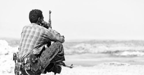 Rear view of man sitting on beach