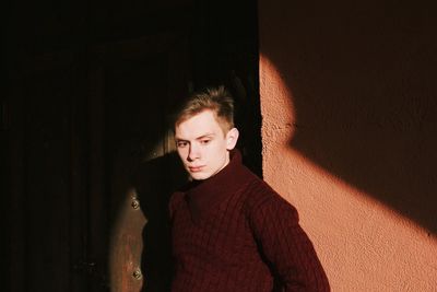 Portrait of young man standing against wall