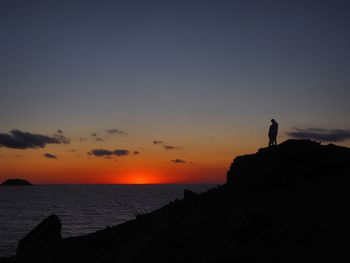 Silhouette man standing on beach against sky during sunset