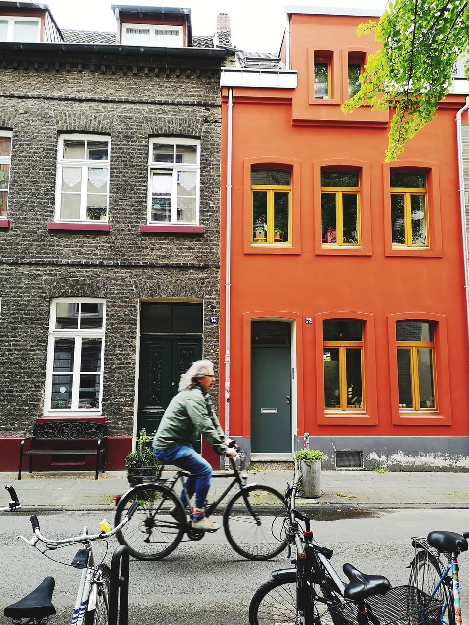 FULL LENGTH OF MAN RIDING BICYCLE BY BUILDING