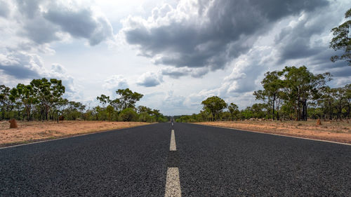 Empty road amidst trees against sky