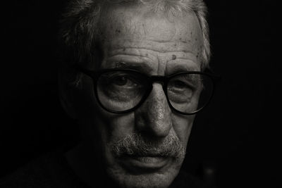 Portrait of man wearing eyeglasses against black background