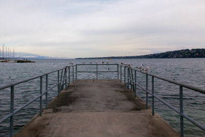 Pier on sea against cloudy sky