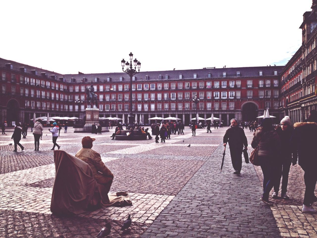 building exterior, architecture, built structure, large group of people, men, person, street, walking, city, clear sky, cobblestone, city life, lifestyles, mixed age range, medium group of people, outdoors, town square, leisure activity, road