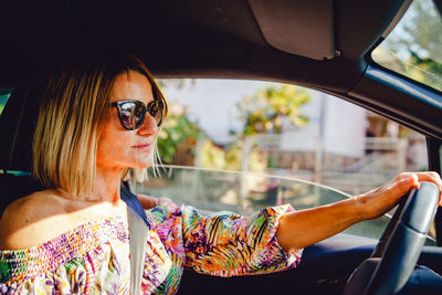 Midsection of woman wearing sunglasses in car