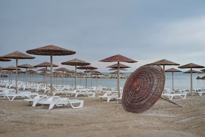 Parasols and chairs on beach against sky