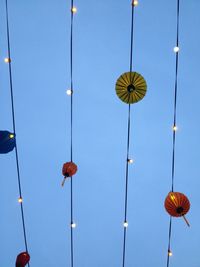 Low angle view of illuminated lighting equipment hanging against sky