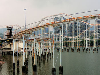 Rollercoaster over river against sky