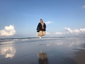 Woman levitating over sea against sky